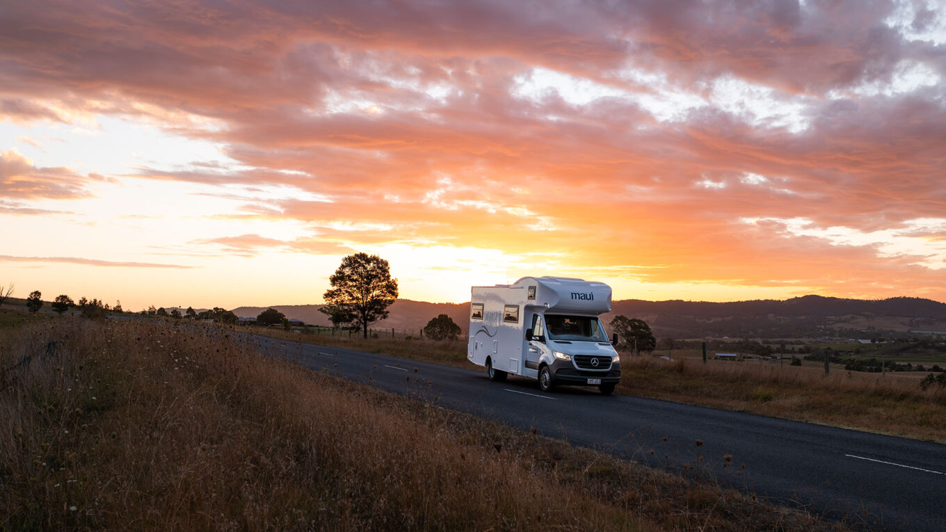 Autocamper på stille landevej i solnedgangens lys - frihed og ro på rejsen gennem Australien.