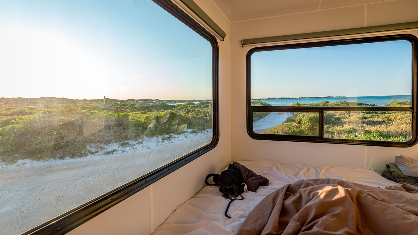 Udsigt til strand og solopgang fra sengen i en autocamper - frihed og komfort i ét.