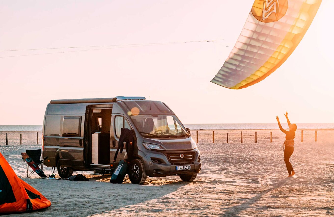 Campervan på stranden med kitesurf