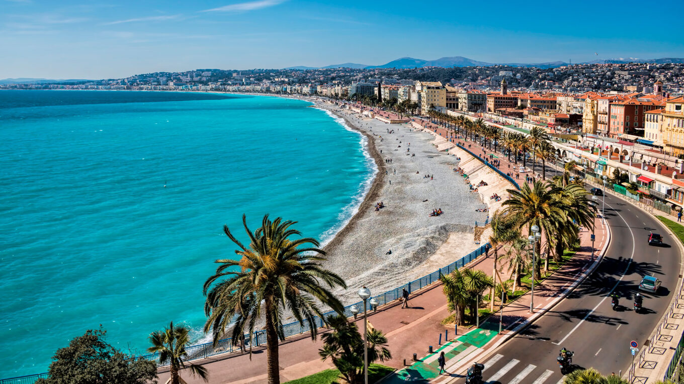 Strandpromenaden i Nice med palmer, turkisblåt hav og strandgæster på Cote d’Azur