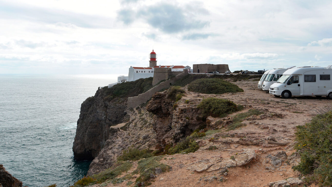 Autocampere ved klippekysten i det sydlige Portugal med udsigt til Atlanterhavet og fyrtårn