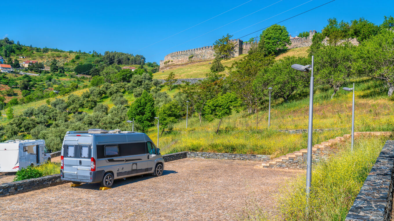 Autocampere parkeret på grøn stellplads nær historisk bymur i Nordportugal