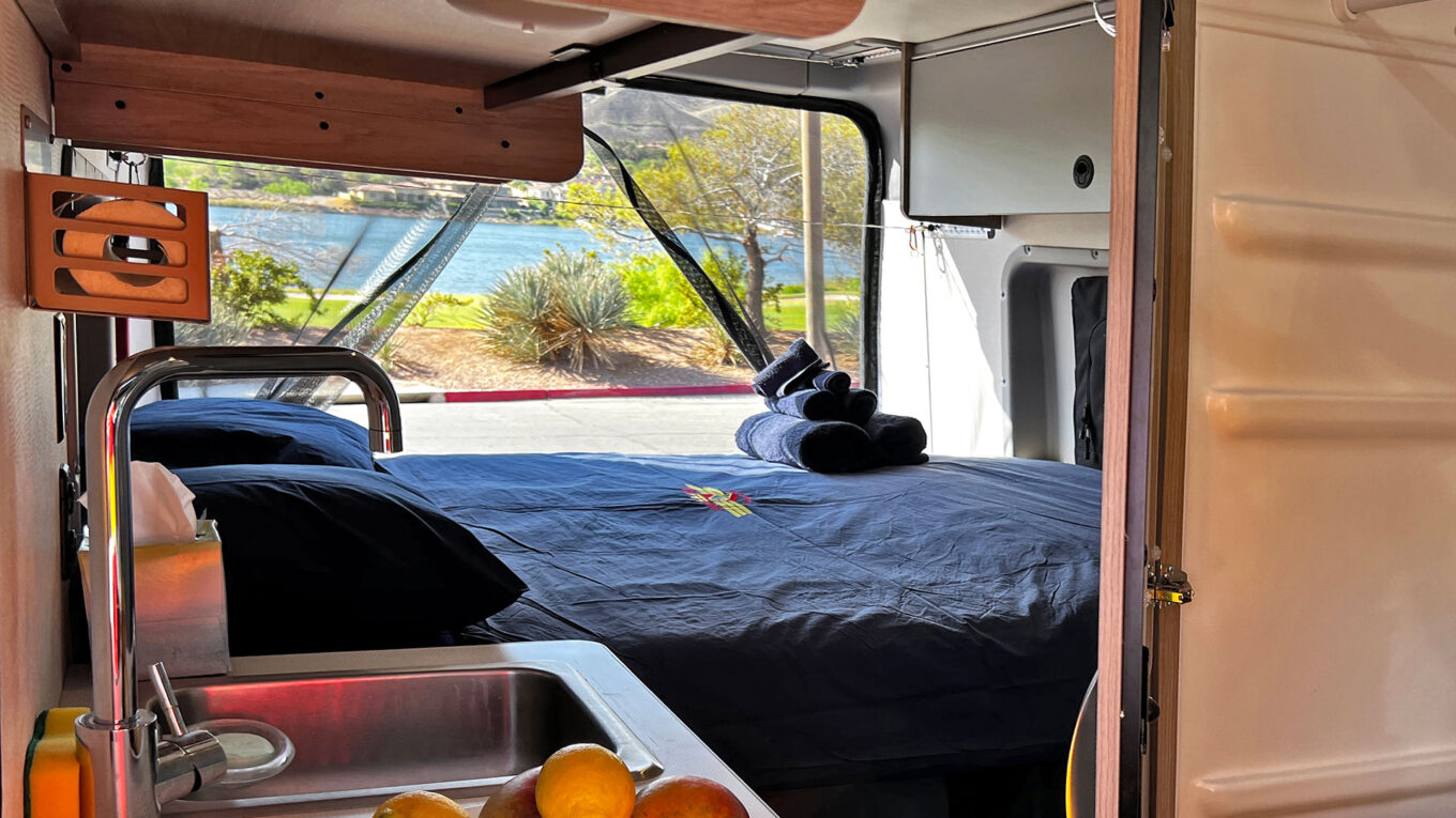 ndvendig udsigt fra en moderne autocamper med dobbeltseng og søudsigt – perfekt til roadtrip i USA.